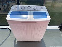 Front view showing the twin tub washing machine with white body and blue lids, control knobs on top.