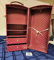 Open view showing interior with 2 drawers, 3 shelves, hook for hanging, and securing ribbon. Fabric lining with small diamond pattern.