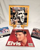 Full view of Elvis 1987 calendar on wooden stand, Life Magazine Elvis book with red cover, two VHS tapes on either side
