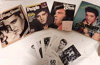 Four Elvis Presley magazines and 19 black and white photos laid out on a table, showing the covers and some photo details