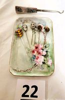 Photo of vintage pins displayed on porcelain dish with pink roses