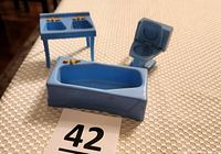 Photo of the blue plastic tub, blue toilet with lid open, and double sink showing gold-colored faucet knobs.