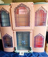 Front facade of the Mattel Grand Hotel playset closed, showcasing pink exterior with purple translucent windows and double front doors.