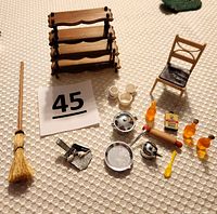 All miniature kitchen items including furniture and utensils displayed on a light fabric surface