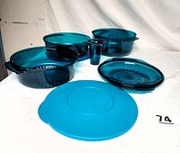 Image showing all pieces laid out separately; large casserole bowl, smaller casserole bowl, colander, cone, and three lids in translucent blue plastic.