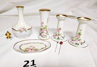 Full set photograph showing perfume decanter, stopper, small dish, pair of candle holders, hat pin holder, and two hat pins on white background.