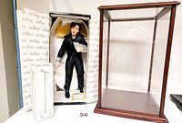 Elvis Presley doll standing in original box next to wood and plexiglass display case and boxed microphone on stand