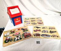 Group photo showing three wooden peg puzzles with vehicle and farm themes next to a Playskool postal station mailbox toy.