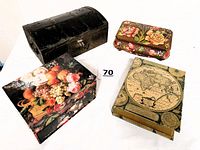 Four vintage decorative boxes grouped together showing different designs including a floral box, book-style box with map, wooden box, and metal chest.