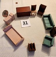 All nine pieces of wooden Strombecker dollhouse furniture arranged on a textured surface showing the scale with a penny.