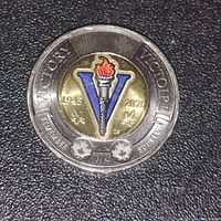 Front side of the colorized Canadian Victory Toonie showing the central colored 'V' with torch and date years 1945 and 2020, with inscription surrounding the outer ring.