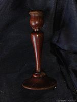 Clear image of antique mahogany candle stick holder with visible signs of wear and wood grain details.