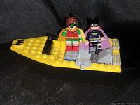 Front-left angle photo showing Batman and Robin minifigures seated in yellow LEGO speed boat with Batman logos.