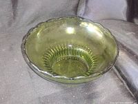 Photo of the olive green glass bowl showing the scalloped edges, textured base, and overall translucent green color.