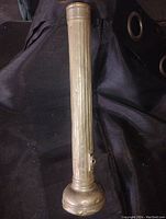 Full view of vintage metal flashlight standing upright showing ribbed body and flared head