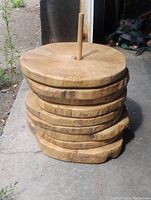 Stack of eight round live edge wooden disks with natural wood texture and rough edges, held together by a central wooden dowel.