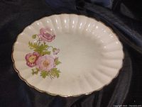 Off-white ceramic oval platter with scalloped edges and a floral motif on one side. Shows some discoloration and signs of age.