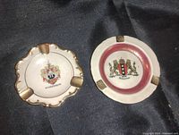Top view showing both ashtrays with coat of arms and gold trim accents.