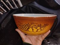 Side view of the 10 inch Pyrex mixing bowl showing brown fruit design on orange-yellow gradient background.