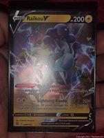 Front view of Raikou V full art holographic foil Pokemon card held in hand.
