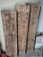 Three rustic reclaimed lumber boards standing upright showing weathered surfaces, rough sawn texture, and natural grain patterns.