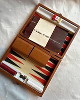 Open backgammon set with board, playing pieces, dice, doubling cube, dice cups, and instruction booklet inside wooden case