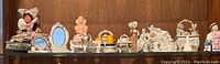 Full view of shelf with various decorative ceramic figurines and small vanity mirrors.