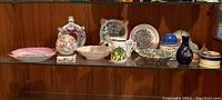 Showcase of all ceramic decorative items and seashell sphere on glass shelf