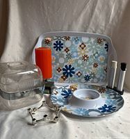 Photo of the complete lot showing two floral melamine trays, a clear acrylic ice bucket with metal handle, an orange candle, silver-tone candle holder and salt & pepper shakers on satin cloth background