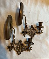 Pair of ornate metal wall sconces laid flat, view of overall design and structure.