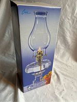 Photo of the oil lamp in its original box showing the packaging with brand name and product image.