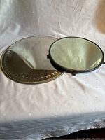 Photo showing both mirrors on fabric background with visible reflections and shadows.