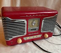 Front left angle view shows the whole red stereo radio and CD player with chrome speaker grills and control knobs.