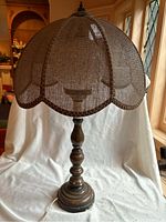 Full view of vintage table lamp showing wooden base and dome shaped brown mesh lamp shade with scalloped edge.