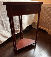Overall view of the wood corner table showing drawer, legs, and lower shelf.