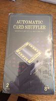 Front view of unopened box showing automatic card shuffler image and text indicating it shuffles up to 2 decks.
