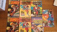 Seven Captain Canuck comic books laid flat on a wooden surface showing covers clearly. Two copies each of issues #5 and #8 are included.