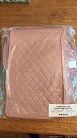 Rectangular pink quilted fabric china protector inside sealed plastic packaging with product label.