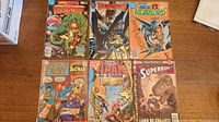 Photo of 6 DC Comics comic books laid out on a wooden surface. Titles include Adventure Comics, Hawkworld, The Warlord, World's Finest, Arak Son of Thunder, Superboy.