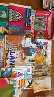 Top view of multiple folded decorative towels displaying varied colorful motifs including landmarks, flags, and cultural symbols