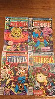 Photo showing all four Marvel Eternals comic books laid out on a wooden surface with visible cover art and titles.
