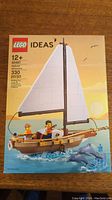 Front of sealed LEGO Ideas 40487 Sailboat Adventure box showing sailboat with two minifigures and dolphins in ocean water scene, piece count 330.