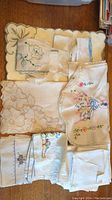 Multiple embroidered napkins and linens with floral designs and scalloped edges