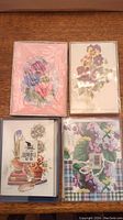 Four sealed card sets with pansy illustrations on a wooden surface. The packs are still in plastic wrapping and show various floral artwork including bouquets and gardening themes.