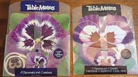 Two boxed sets of Table Mates Pimpernel pansy flower placemats and coasters, unopened, showing front packaging with designs.