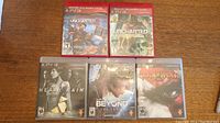 Five PS3 game cases laid out on a wooden surface: Uncharted series (Drake's Fortune and 2), Heavy Rain, Beyond Two Souls, and God of War 3.