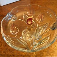 Top-down view of the candy dish showing clear yellow-tinted glass with embossed tulip floral motif inside and smooth scalloped edges. Waltherglass label is visible inside the bowl.