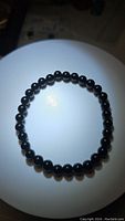 Top view of natural black onyx beaded stretchy bracelet showing smooth round beads and elastic cord