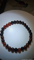 Photo of the full stretchy bracelet made of round dream agate beads showing colors from black to reddish tones.