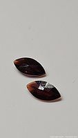 Pair of marquis cut orange-red almandine garnet gemstones, shown on white background.